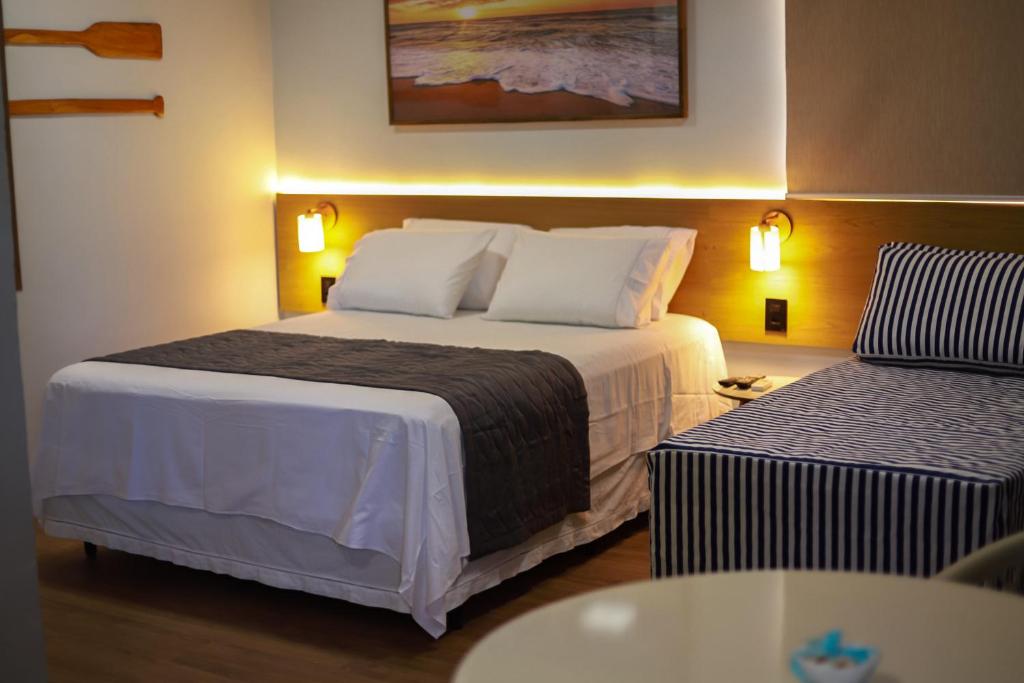 a hotel room with a large bed and a table at O Azul de Maragogi - Pousada Premium in Maragogi