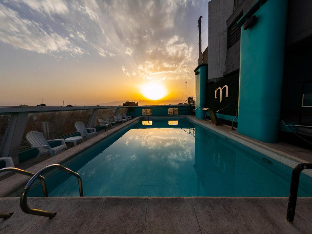 a swimming pool on the roof of a building with the sunset at Hotel Metropol in San Miguel de Tucumán