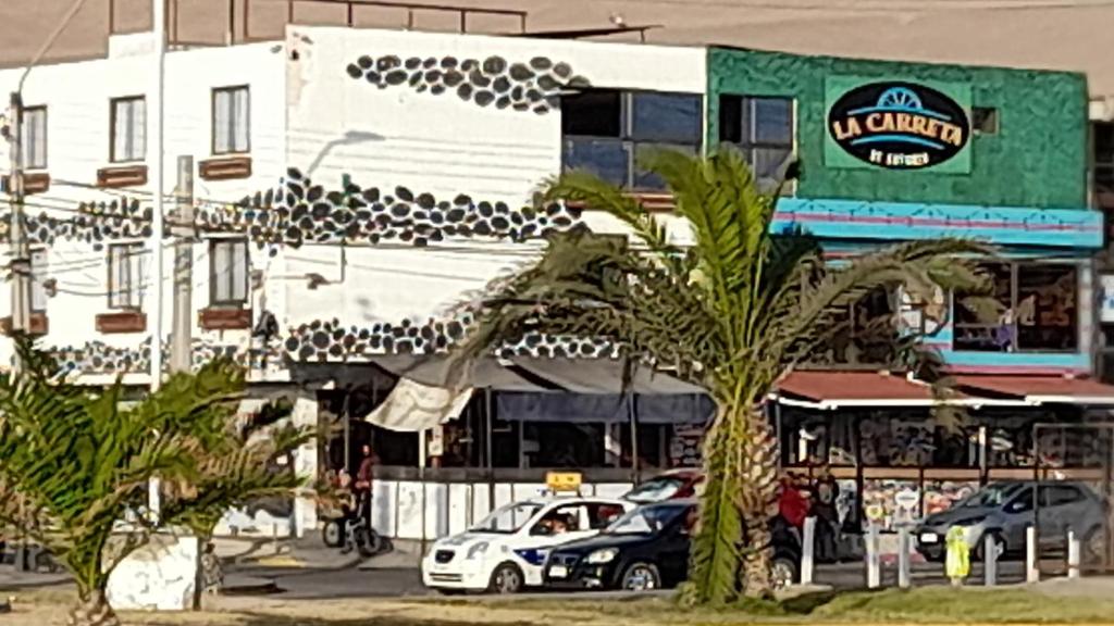 un edificio blanco con coches estacionados en un estacionamiento en Hotel La Carreta Playa Brava, en Iquique