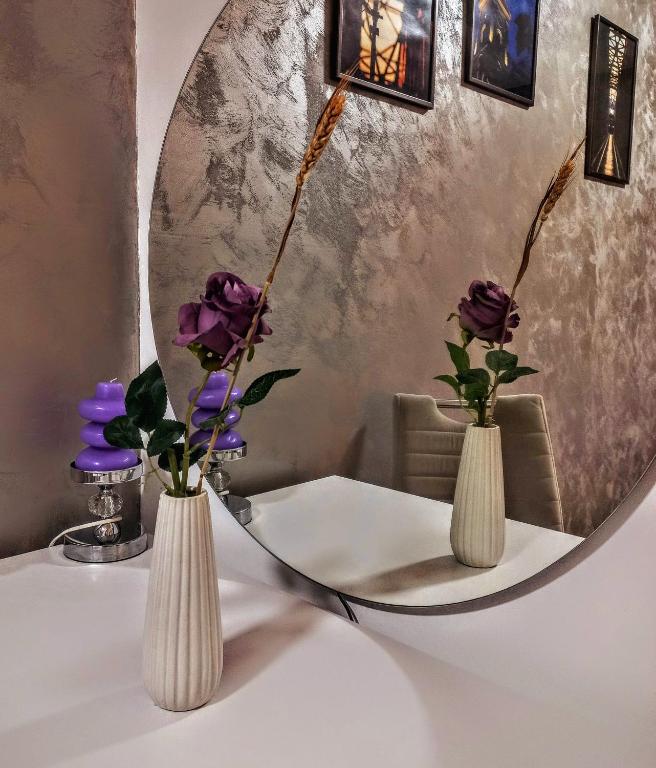two vases with flowers on a table in front of a mirror at TOP Apartman in Šabac