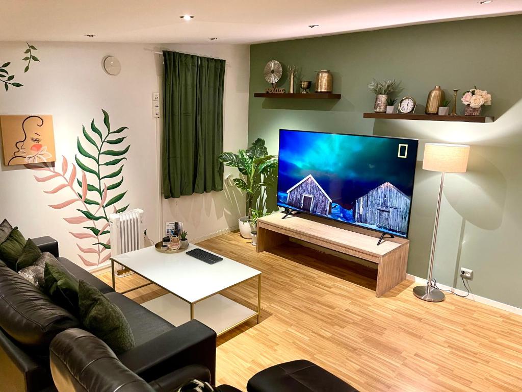 uma sala de estar com uma grande televisão de ecrã plano em Guesthouse in Tromso center by Dada em Tromsø