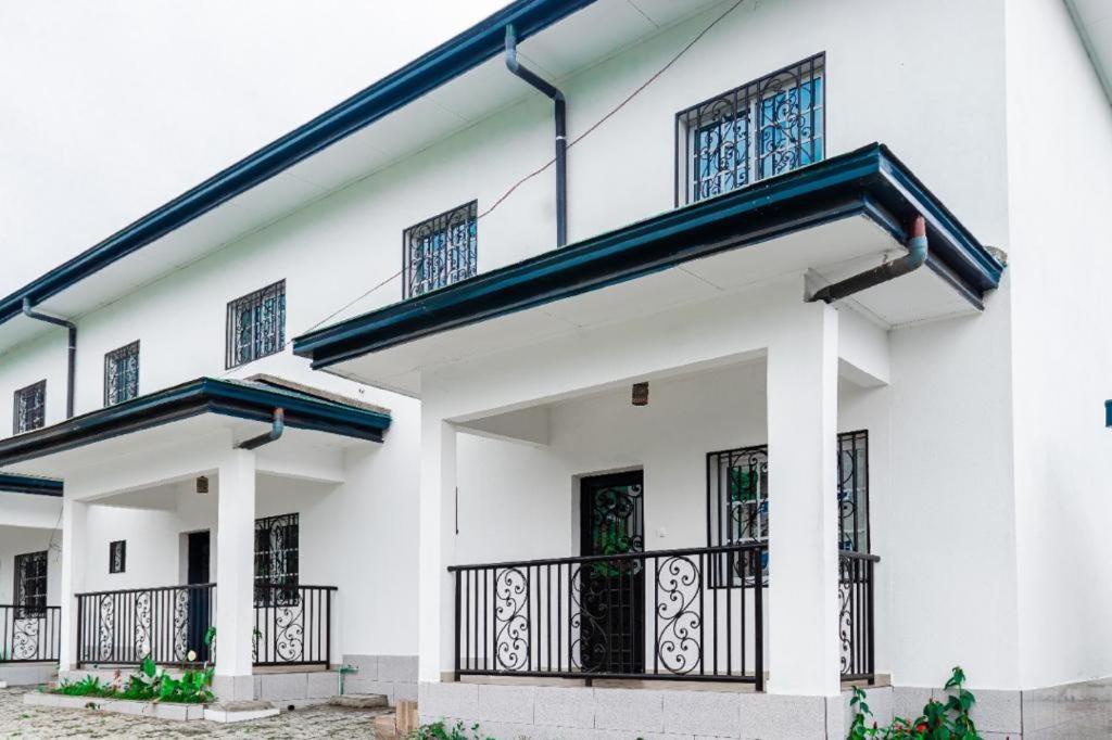 a white building with black windows and a balcony at E&T Resorts in Buea
