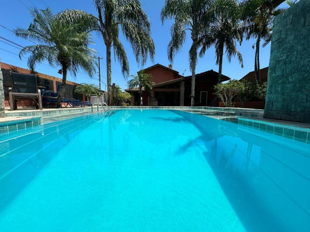 a large blue swimming pool with palm trees at Casa com piscina em boraceia a 400 metros da praia in Boracéia
