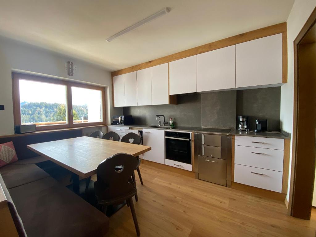 une cuisine avec des placards blancs et une table en bois dans l'établissement Ampio appartamento di 200mq nel cuore di Antermoia, à Antermoia