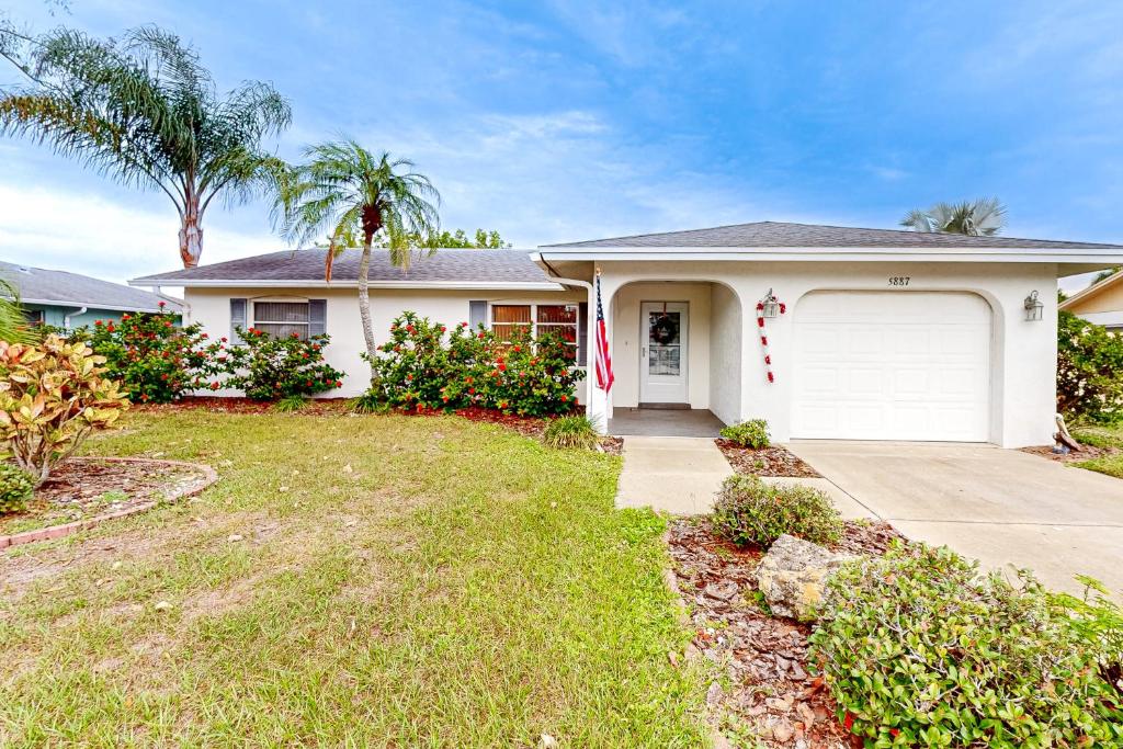 een wit huis met een garage en palmbomen bij East Side Escape in Sarasota