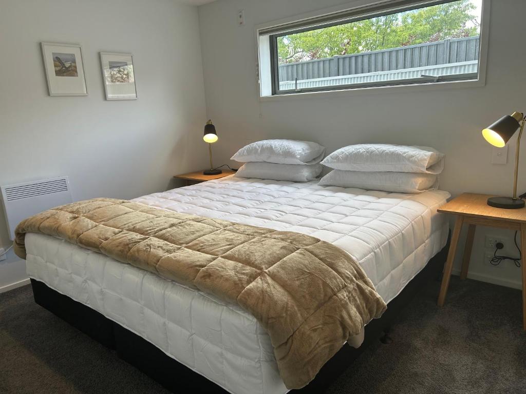 a bedroom with a large white bed with a window at Aspiring View Apartments in Wanaka