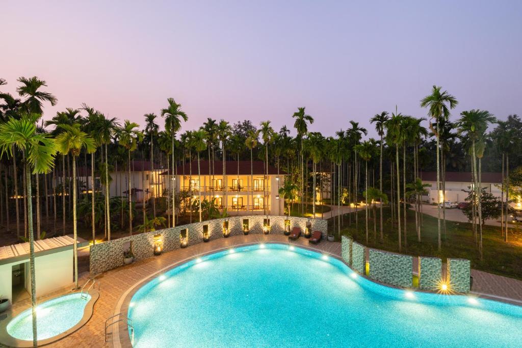 una piscina con palmeras y un edificio en Malnad Shire Eco Resort en Shimoga
