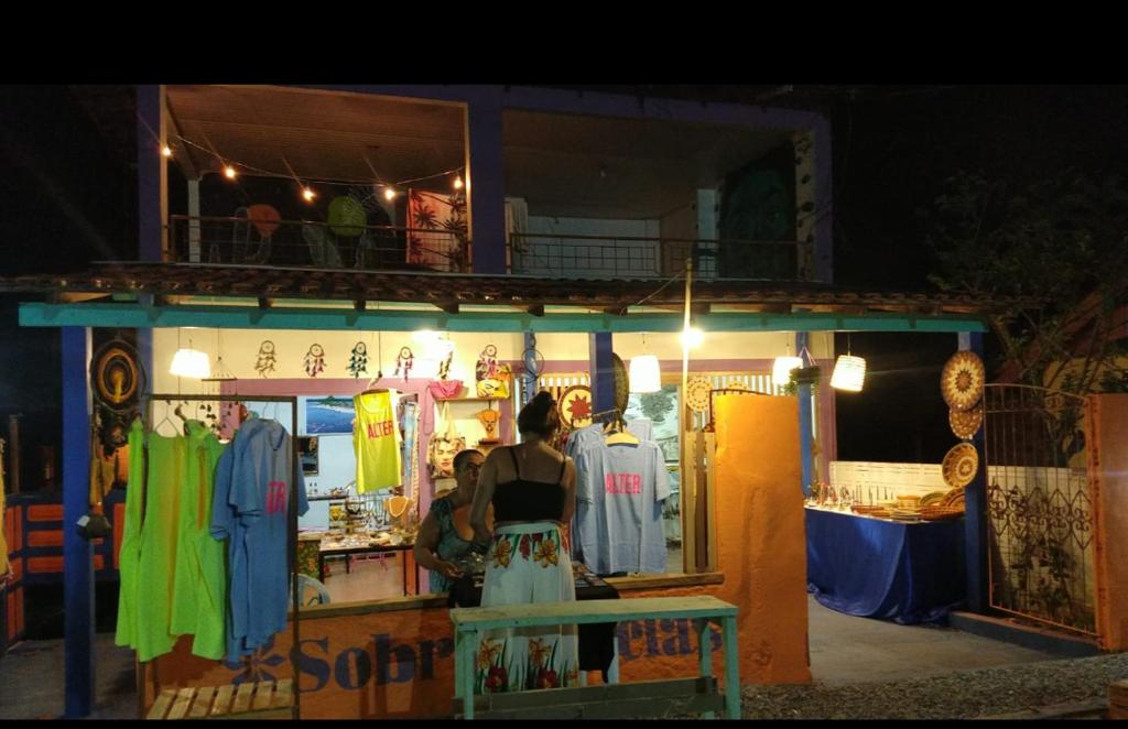 Hospedagem da Lua no Sobrado Delas في ألتر دو تشاو: امرأة تقف أمام محل ملابس في الليل