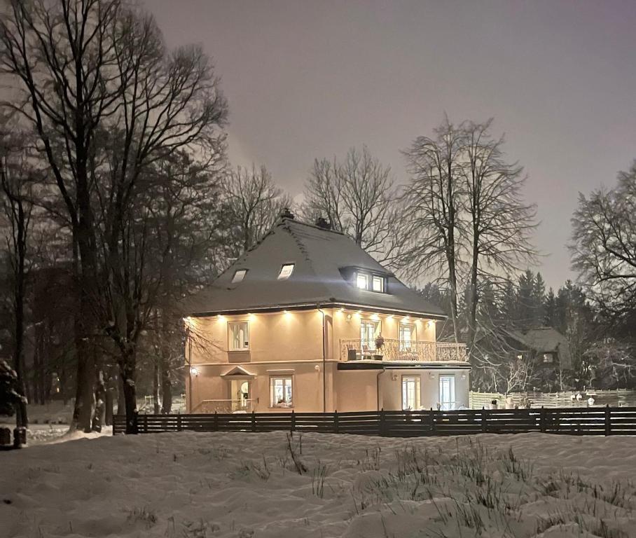 een groot huis met verlichting in de sneeuw bij Villa Śnieżka in Kowary