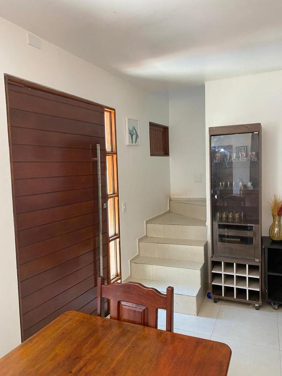 a room with a wooden door and a table and stairs at Casa Lua Nova in São Luís do Quitunde