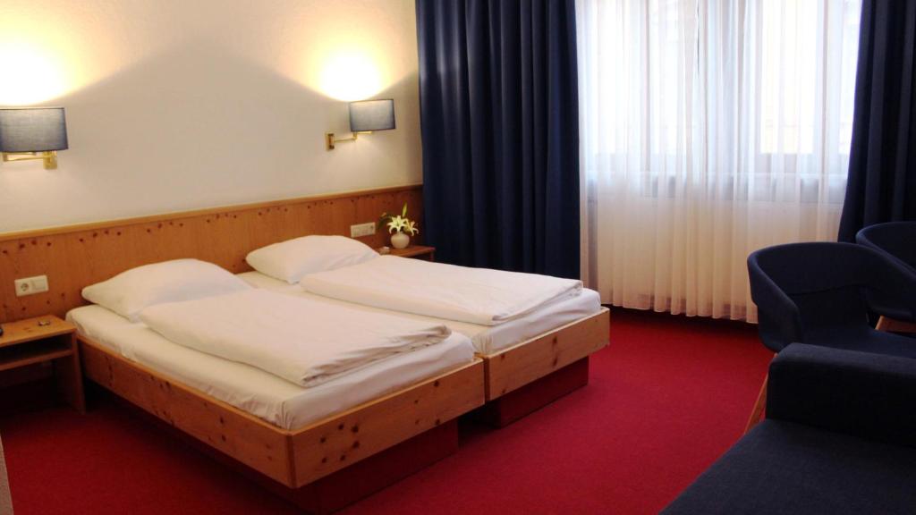 a hotel room with two beds and a chair at Hotel Restaurant Krokodil in Heidelberg