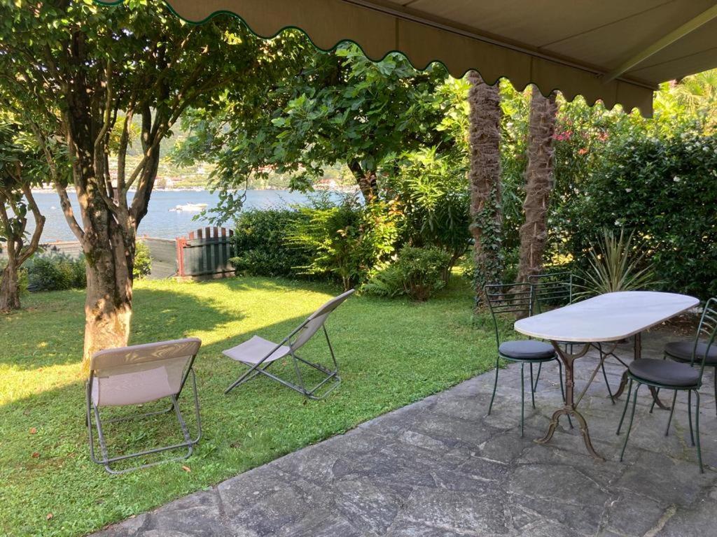 un tavolo e sedie seduti sotto un ombrellone di Orta cottage sulla riva del lago a Orta San Giulio