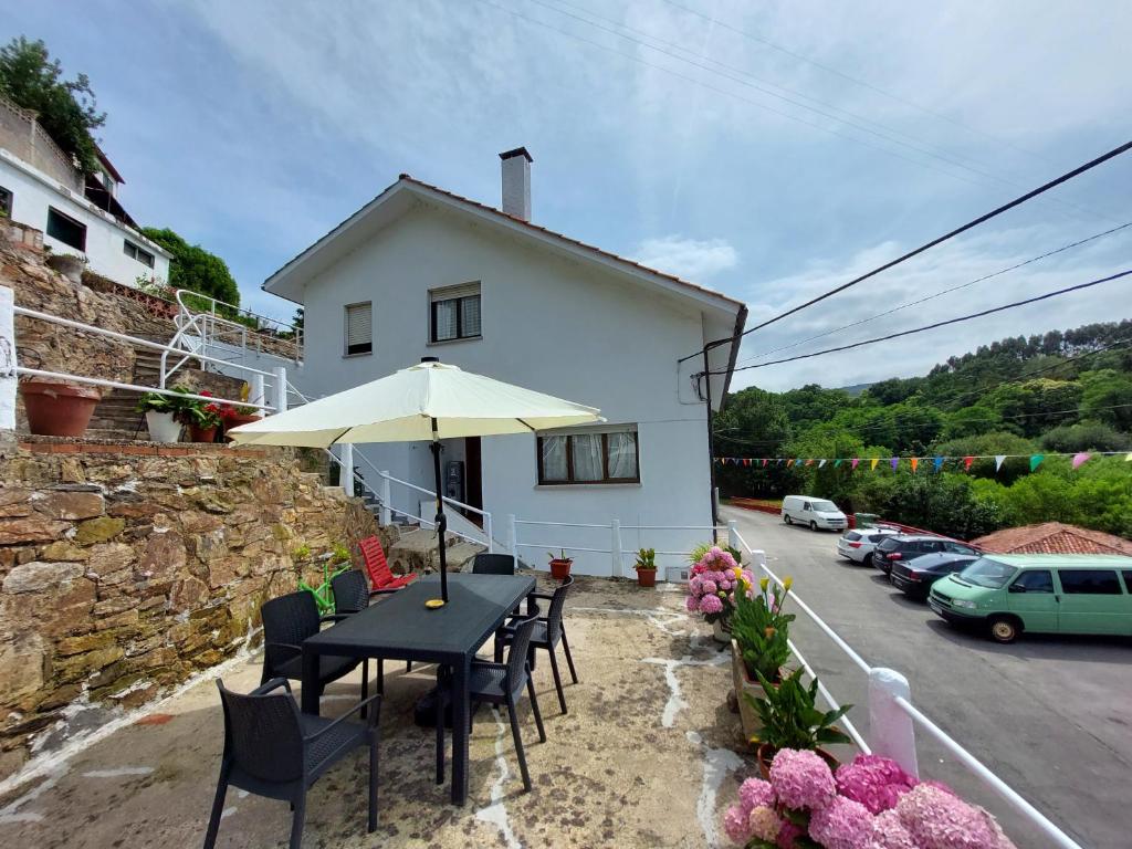 a house with a table and chairs and an umbrella at Pensión El Pozo in Cudillero