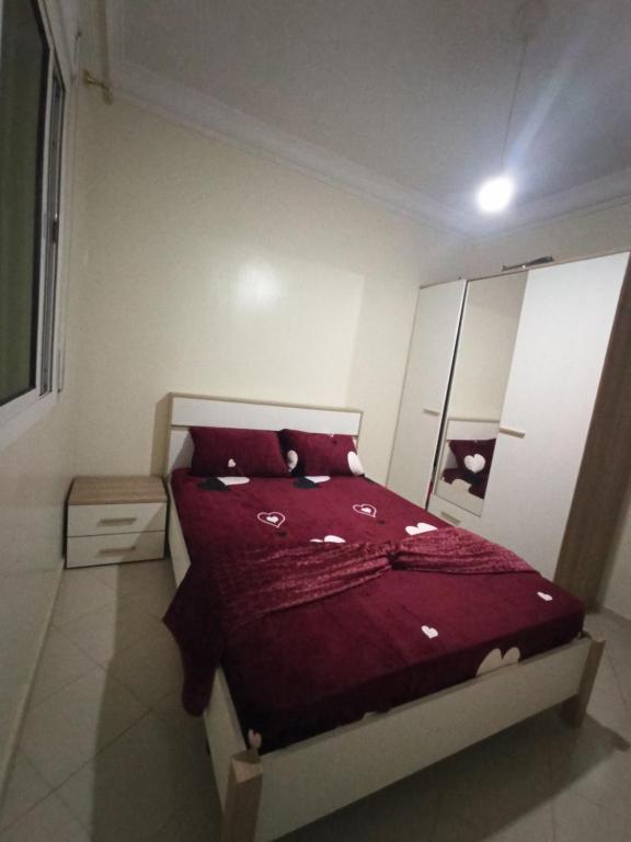 Schlafzimmer mit einem Bett mit einer roten Bettdecke in der Unterkunft Appartement Complète à Tanja balia proche de la mer in Tangier