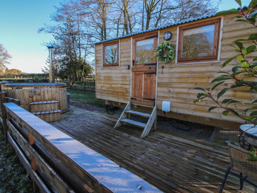 a tiny house with a ladder on a wooden deck at The Oak Hut in Whitchurch