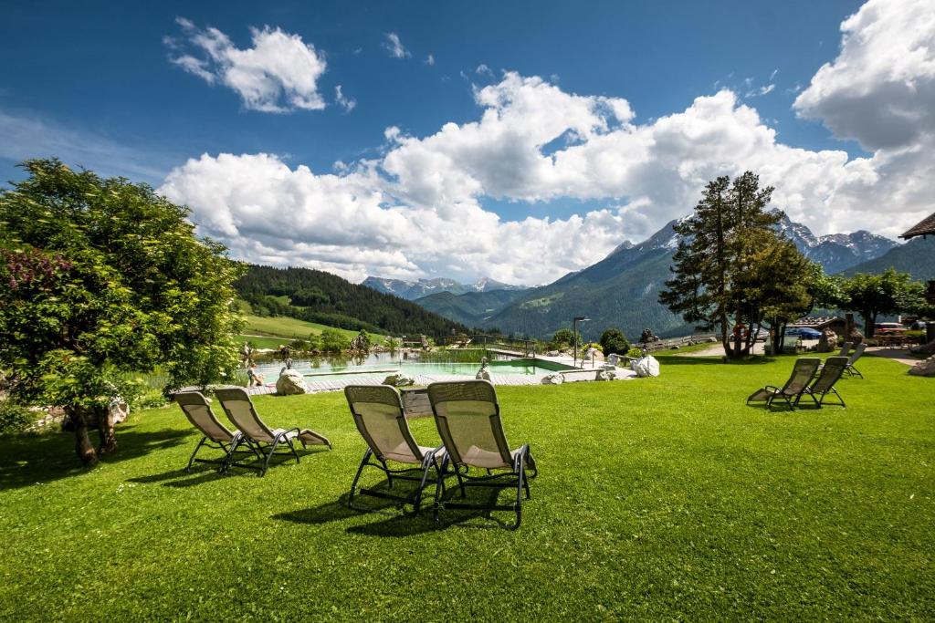 a group of chairs sitting in the grass near a lake at Ettlerlehen Chalets in Ramsau
