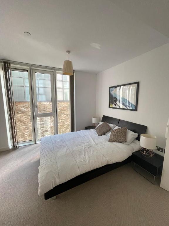 a bedroom with a large white bed with windows at Exquisite 2BD Flat w Balcony Shoreditch! in London