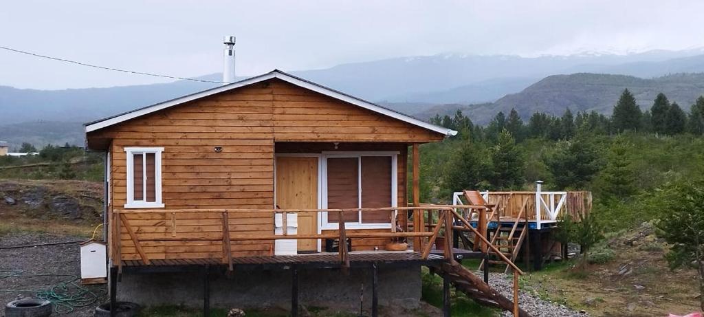 uma pequena casa de madeira com um alpendre e uma varanda em Cabañas y Tinajas FERISI em Cochrane