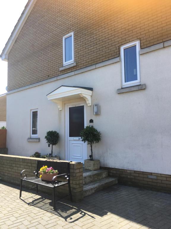 a white house with a bench and a door at 2 Friends Close in Kent