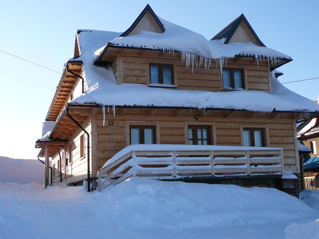 a wooden house covered in snow with icicles on it at Pokoje Gościnne Iwona in Brzegi