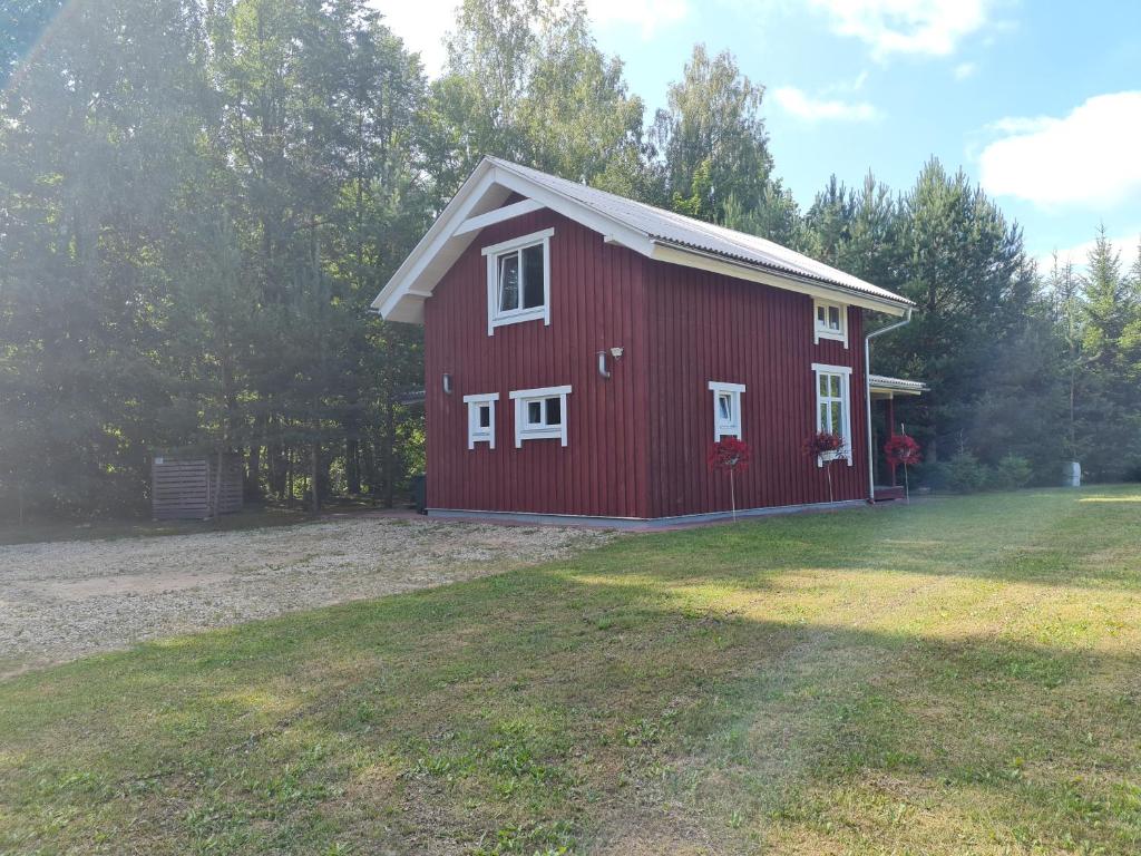a red barn with white windows in a yard at Toma pirts BRĪVDIENU in Ikšķile