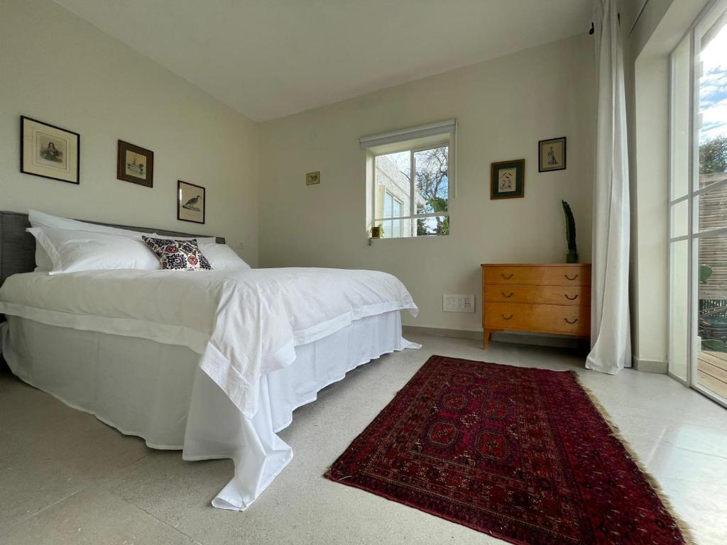 a bedroom with a white bed and a red rug at בקתות האס ואטינגר in Jaba‘