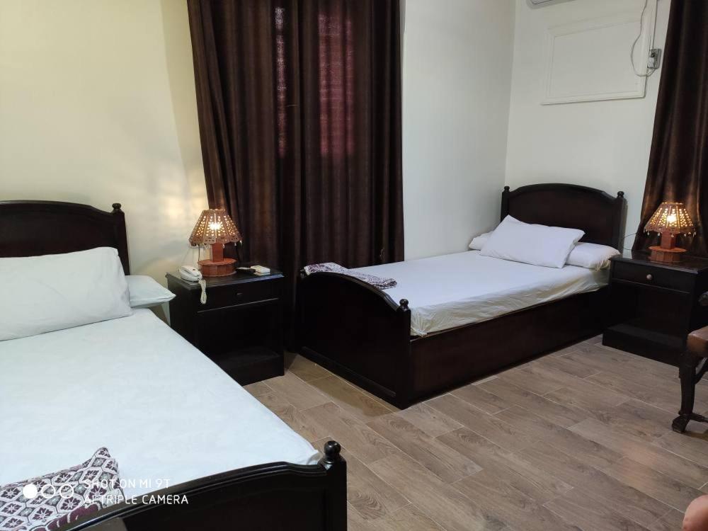 een kamer met twee bedden en twee lampen op tafels bij Salvatore Rooms with Breakfast-City Center in Damietta