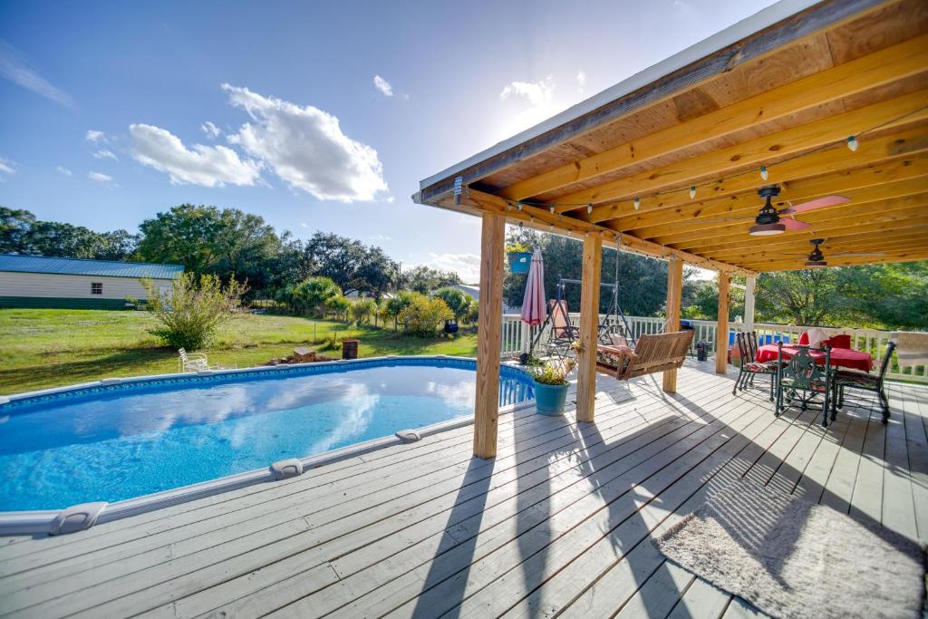 a wooden deck with a swimming pool and a pergola at Moore Haven Getaway with Deck and Private Pool in Moore Haven