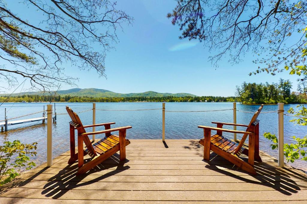 two benches sitting on a dock near the water at Let's Bay Together in Ossipee