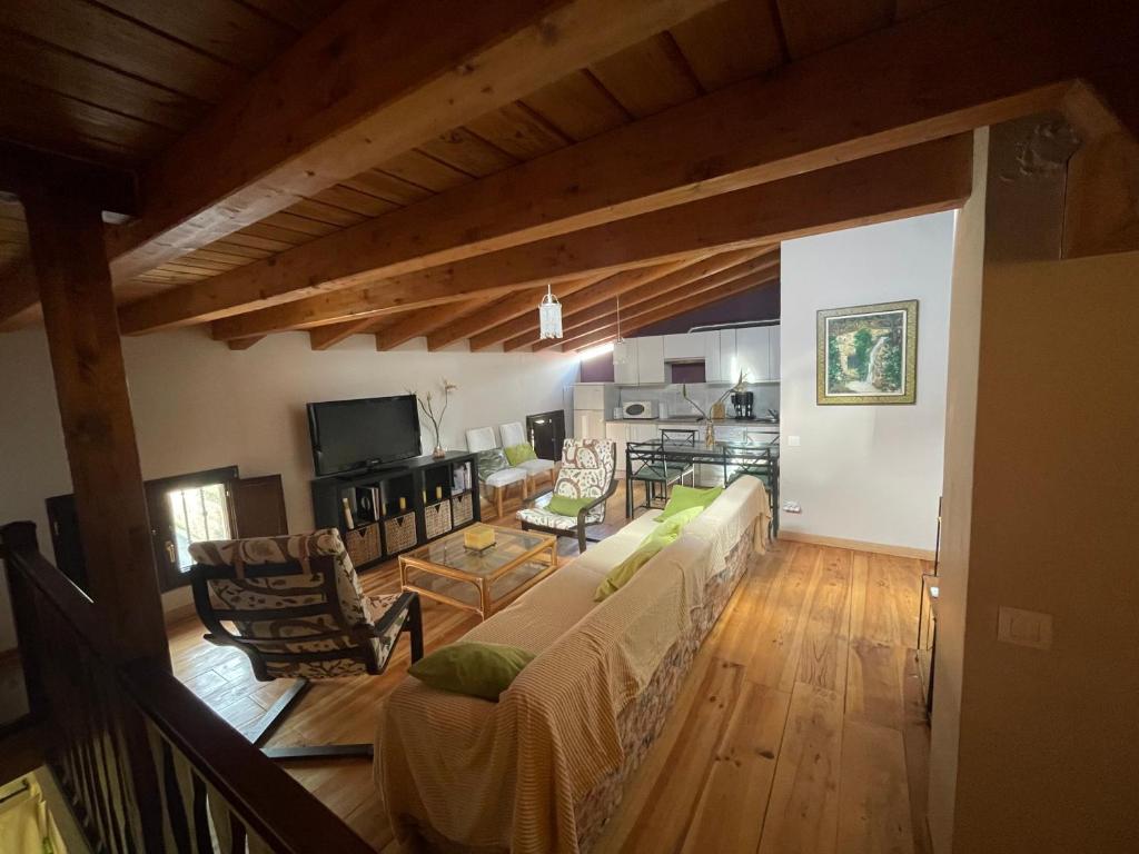 ein Wohnzimmer mit einem Sofa und einem Tisch in der Unterkunft Ático aires de gredos in Candeleda