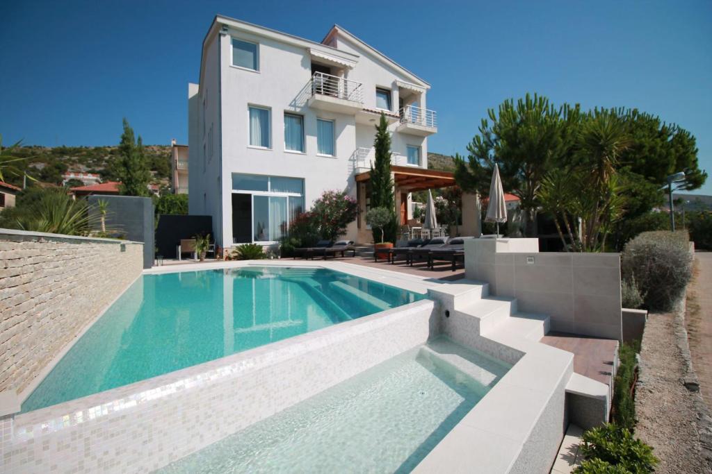 a villa with a swimming pool in front of a house at Apartments Marer in Trogir