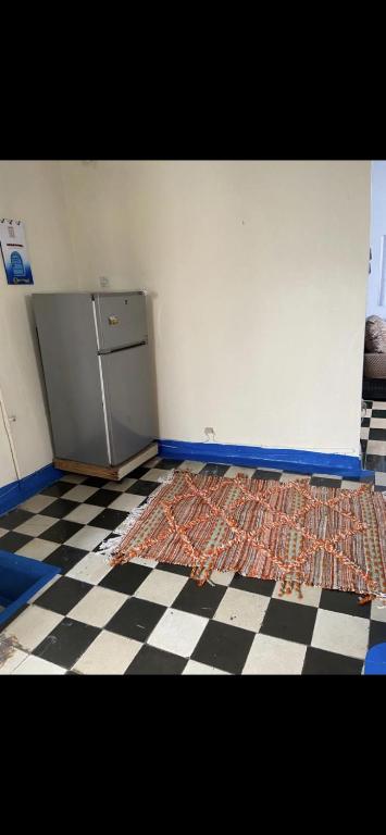 eine Küche mit einem Kühlschrank und einem karierten Boden in der Unterkunft Chez Housna in Rabat