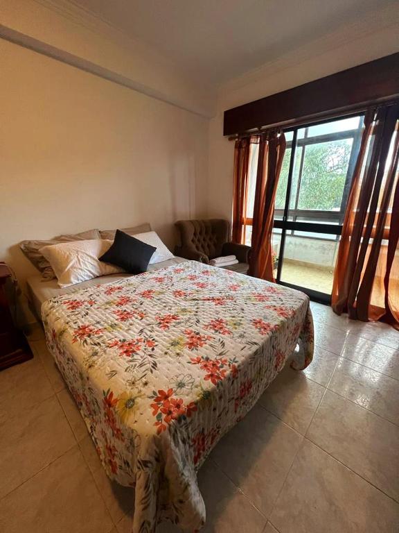 um quarto com uma cama com um edredão floral em Happyhouse em Algueirão