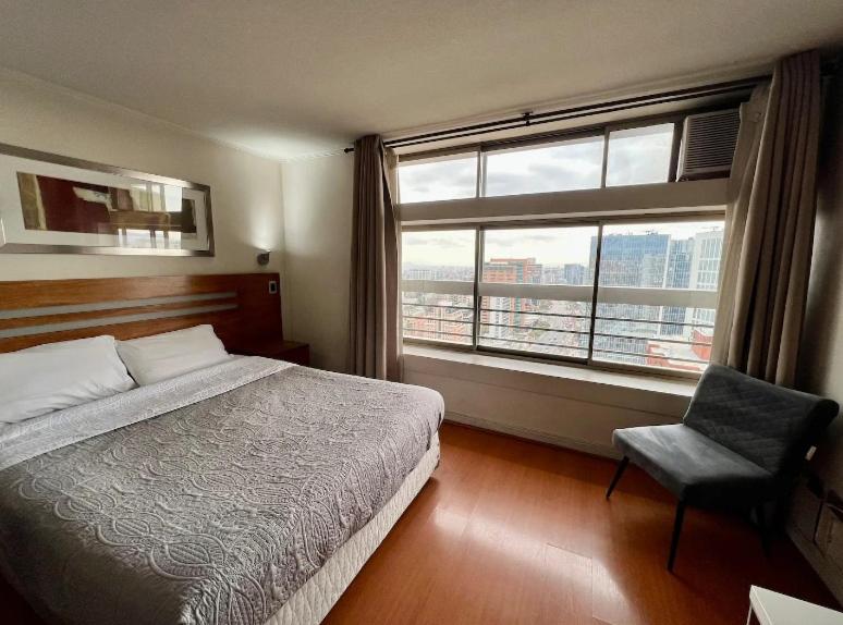 een slaapkamer met een bed, een stoel en een raam bij Apartamento para 2 con gran Piscina in Santiago