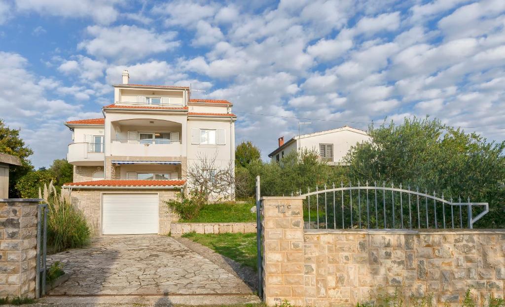 a white house with a gate and a fence at Apartments Maris in Tribunj