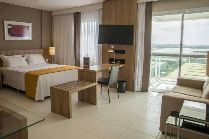 um quarto de hotel com uma cama e uma secretária com um computador em Rio Stay Barra Hotel no Rio de Janeiro