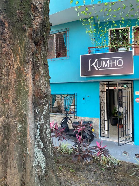 Hostel Kumho alojamiento في ميديلين: مبنى ازرق مع علامة بجانب شجرة