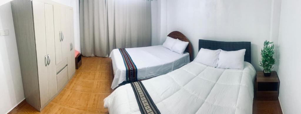a bedroom with two beds with white sheets at SAMAY Casa familiar en el valle sagrado in Calca