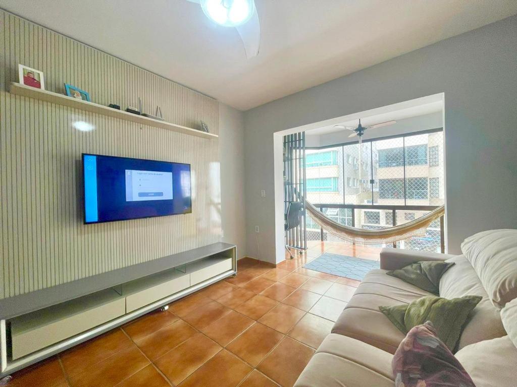 salon z kanapą i telewizorem z płaskim ekranem w obiekcie Ap 2 dormitorios no centro w mieście Capão da Canoa