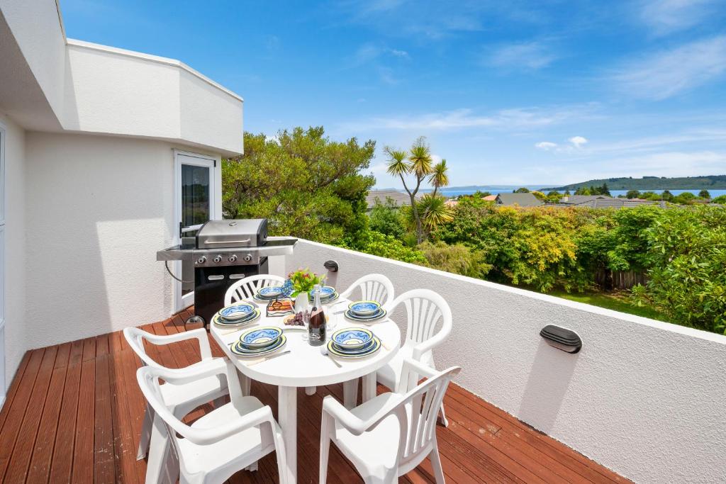 einen weißen Tisch und Stühle auf einem Balkon mit Grill in der Unterkunft The White House - Taupo Holiday Home in Taupo