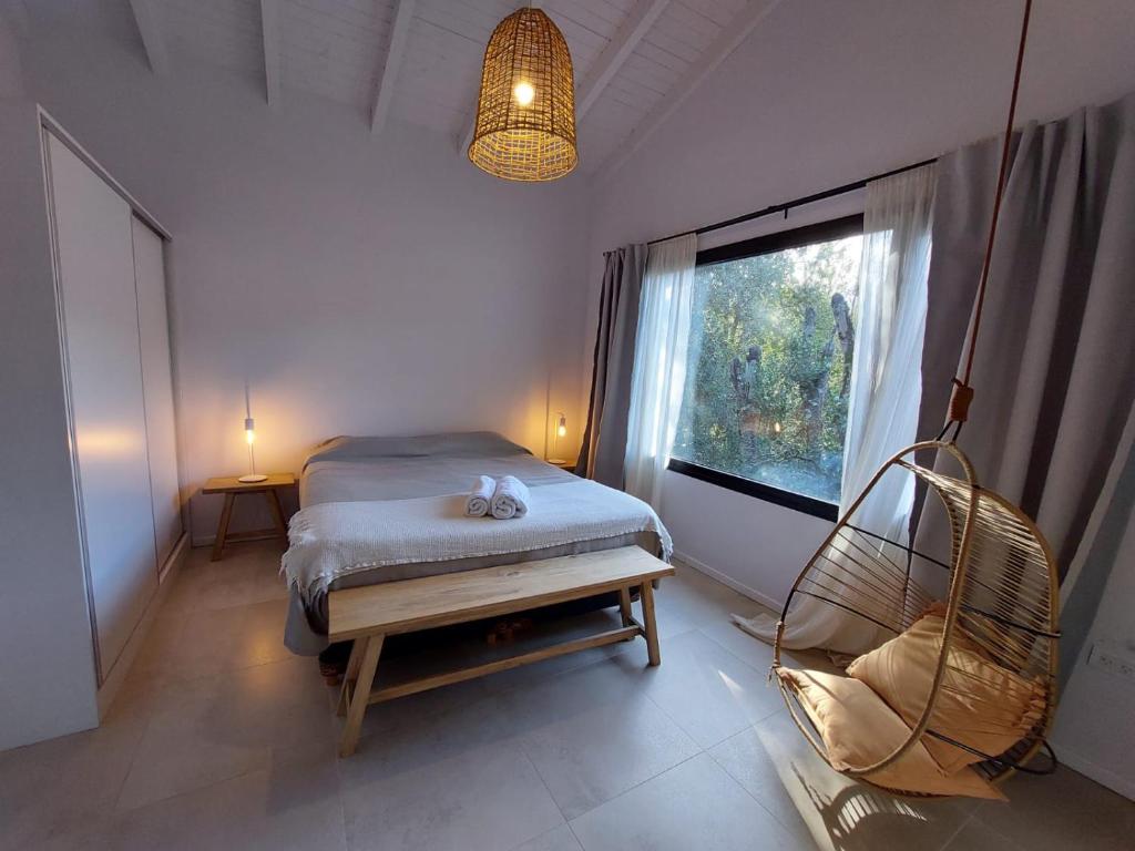 um quarto com uma cama, uma janela e uma cadeira em Al pie del Cerro em Villa La Angostura
