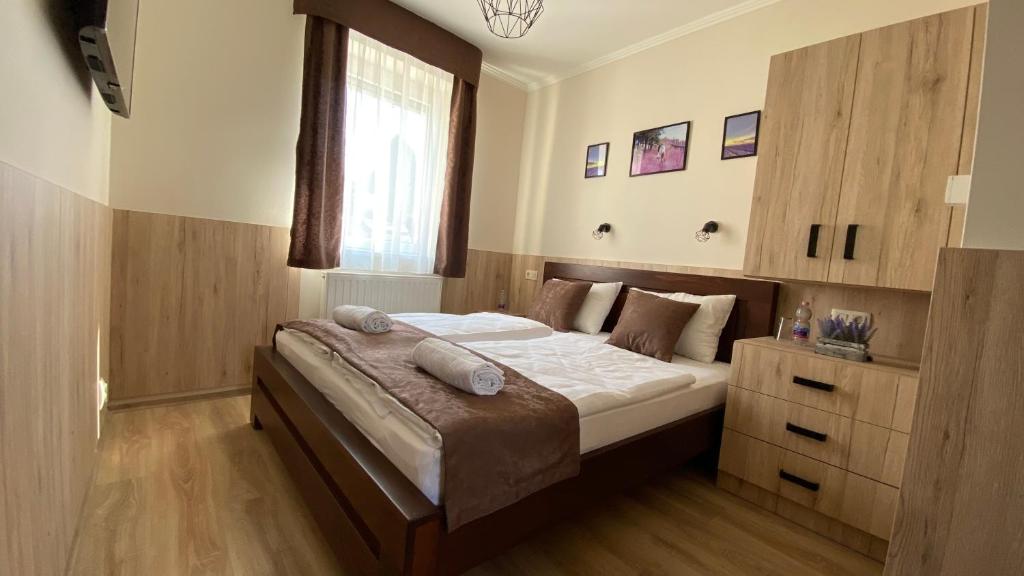 een slaapkamer met een groot bed met witte lakens en een raam bij Levendula Vendégház in Győr