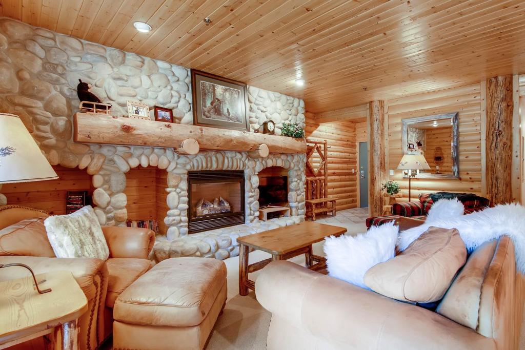uma sala de estar com uma lareira de pedra num chalé de madeira em Black Bear Lodge em Park City