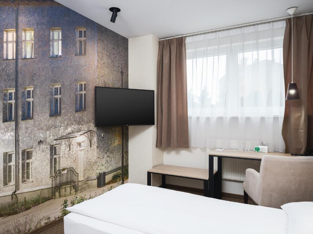 a hotel room with a bed and a tv and a window at Iness Hotel in Łódź