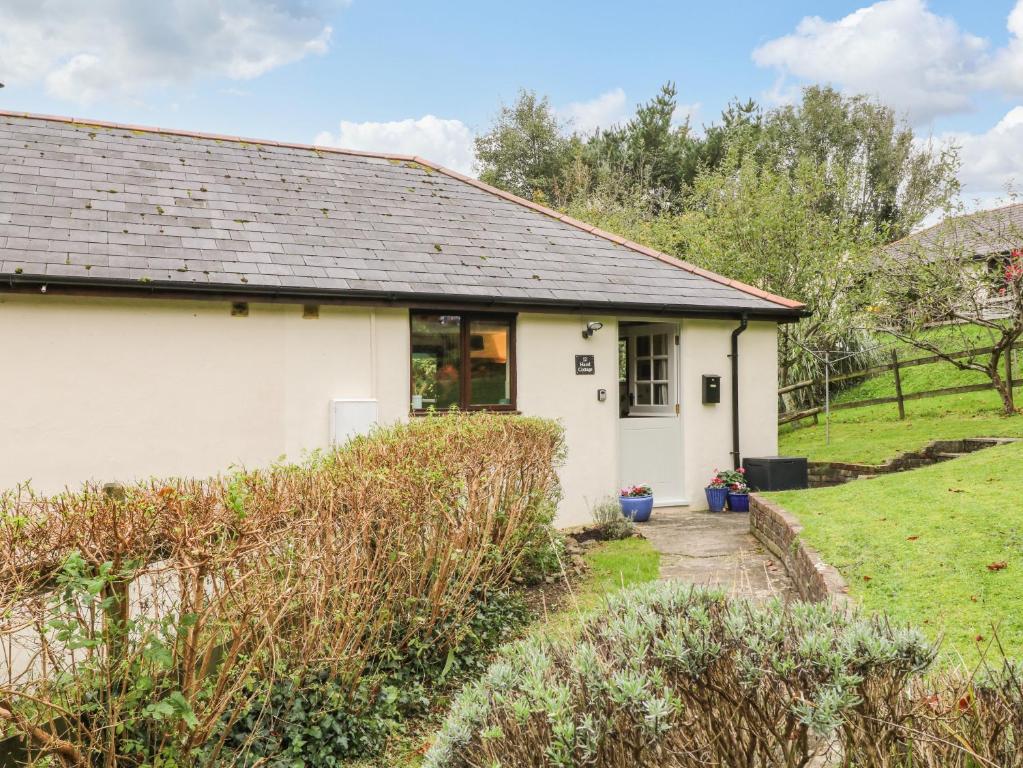 a white cottage with a garden in front of it at Hazel Cottage in Bude