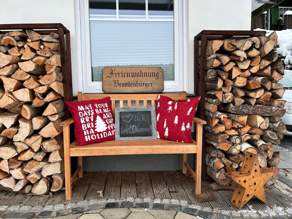 un banco en un porche junto a un montón de troncos en Ferienwohnung Brandenburger en Schmallenberg