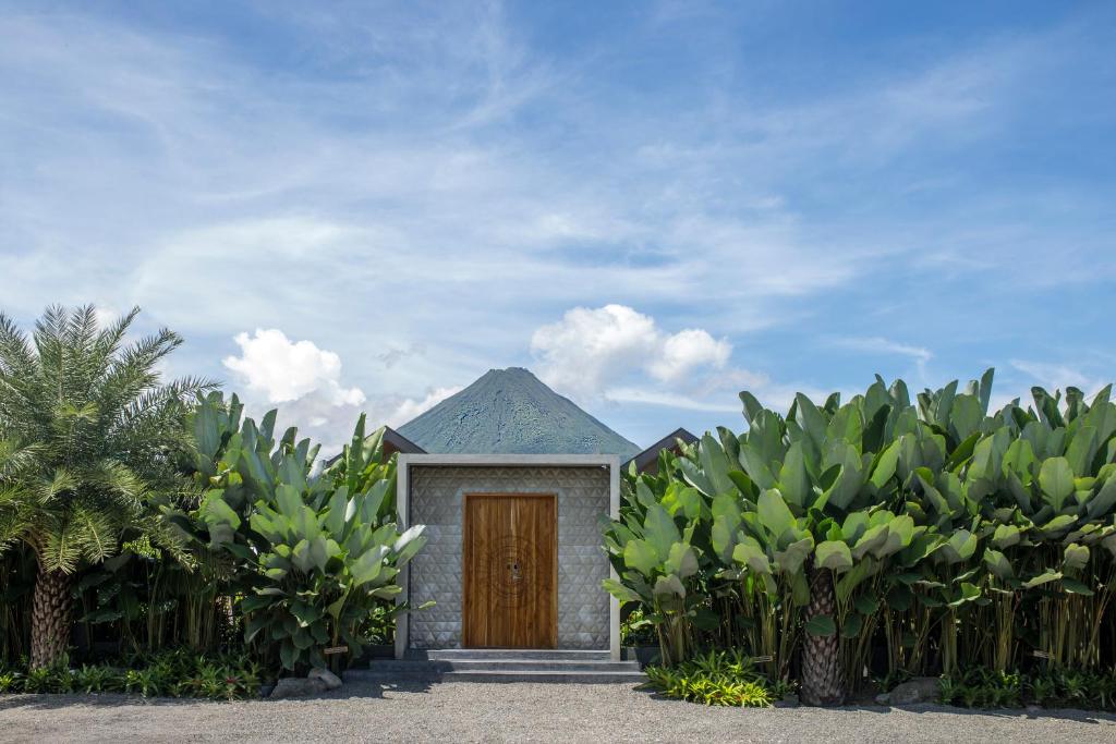 Una pequeña casa con una puerta de madera en un jardín en Suwa Villa Arenal, en Fortuna