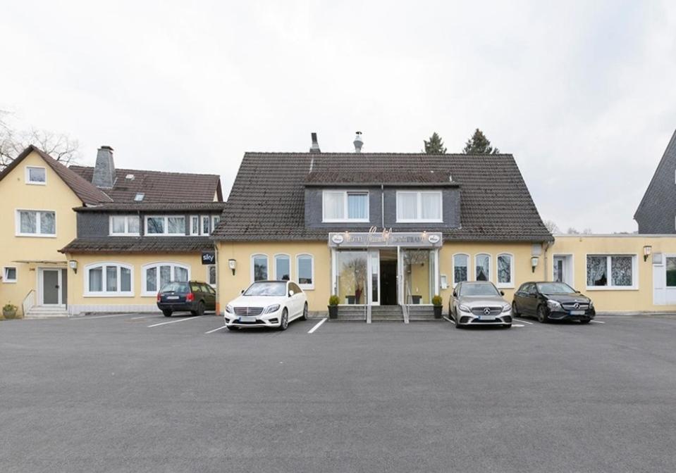 a building with three cars parked in a parking lot at Hotel 9-enhof in Wuppertal