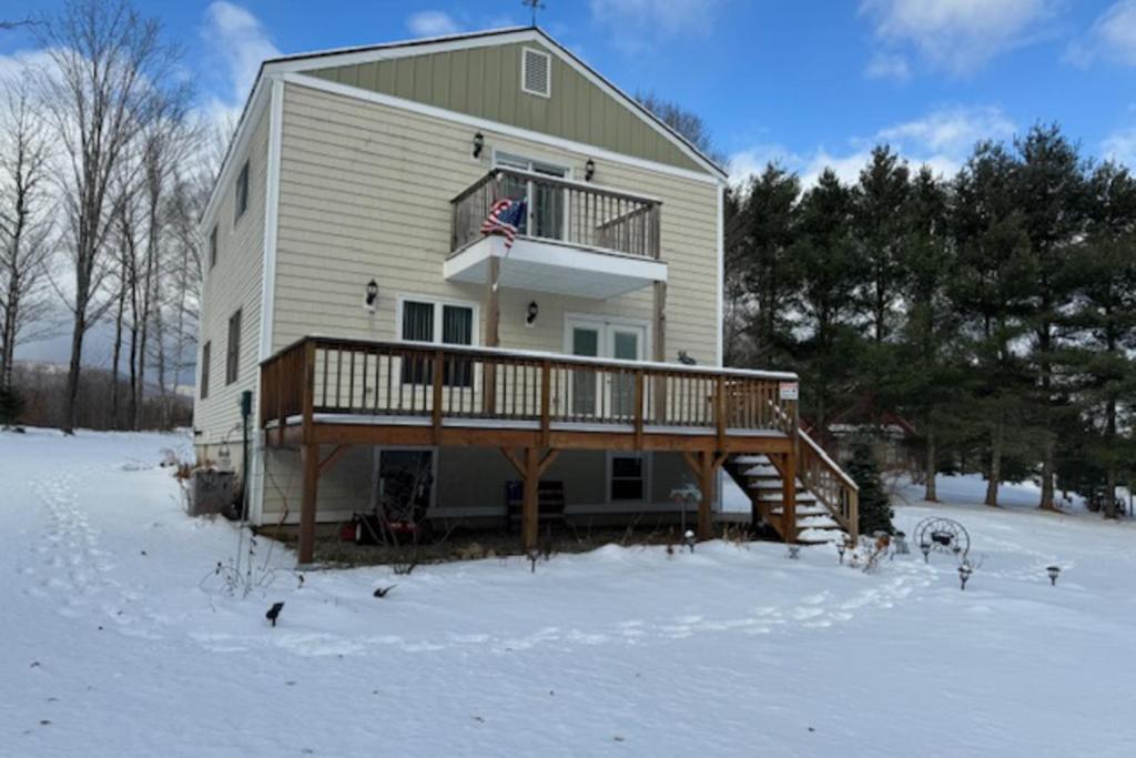 a large house with a deck in the snow at Marlin's Way in Jay