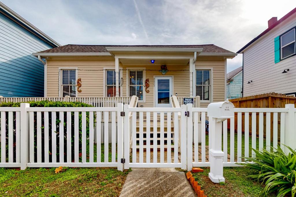 a white fence in front of a house at Betty's Beach House in Galveston